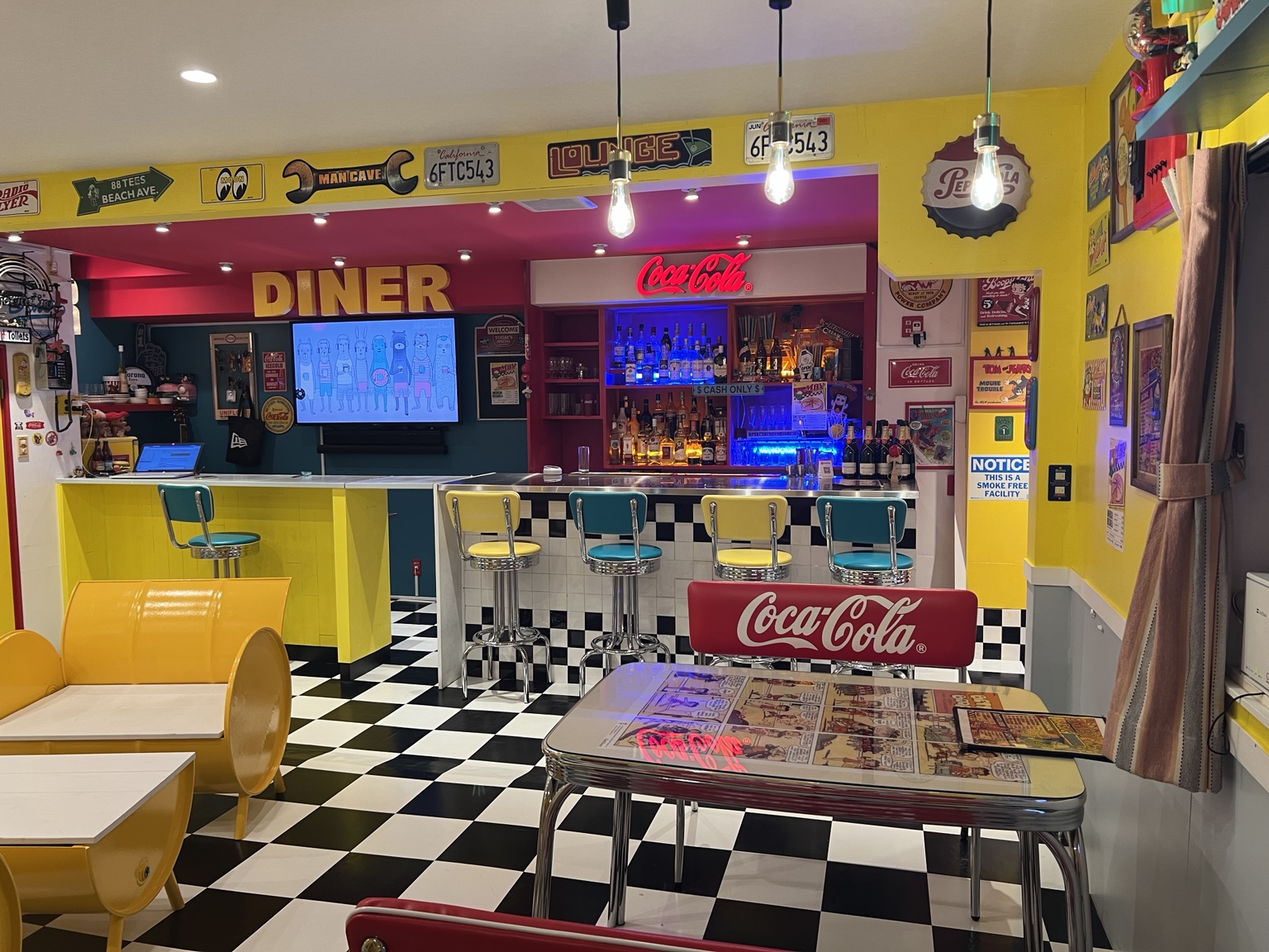 DINERの文字とコカ・コーラのネオン、カラフルなカウンターチェア、手前のテーブル席