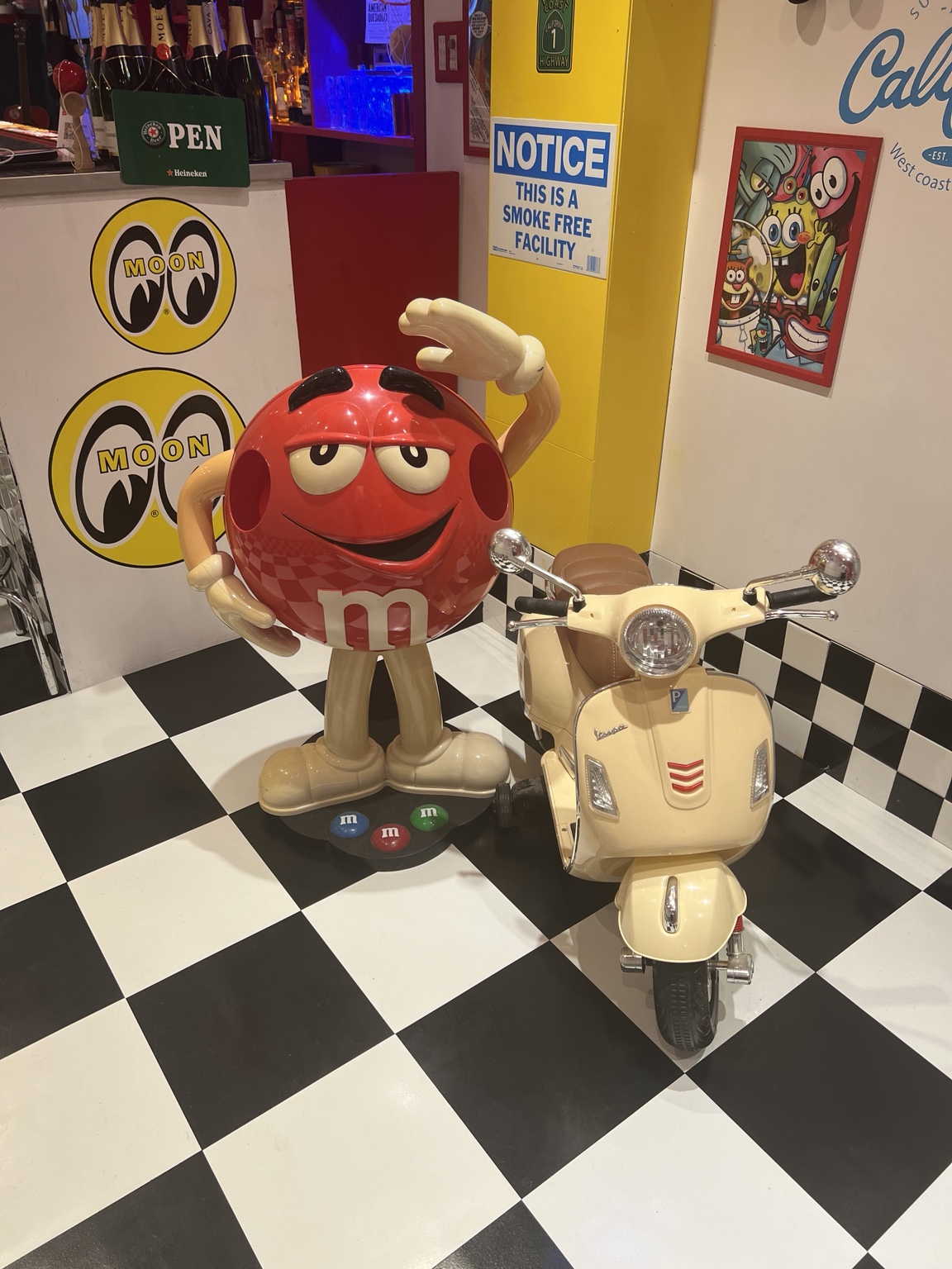 赤いM＆M’sのディスプレイとクリーム色のスクーター